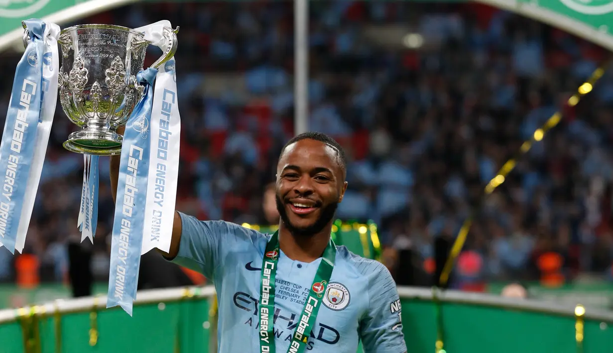 Gelandang Manchester City, Raheem Sterling mengangkat trofi setelah memenangkan pertandingan final Piala Liga Inggris melawan Chelsea di stadion Wembley, London, Minggu (24/2). Manchester City Chelsea lewat drama adu penalti 4-3. (Adrian DENNIS / AFP)