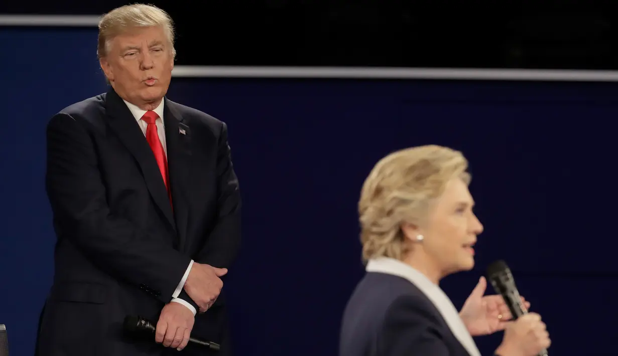 Ekspresi Donald Trump yang berdiri belakang rivalnya, Hillary Clinton selama debat Capres AS putaran kedua di Washington University, St Louis, AS, Minggu (9/10). Bahasa tubuh trump ini memicu keheranan dan ejekan di media sosial. (AP Photo/Julio Cortez)