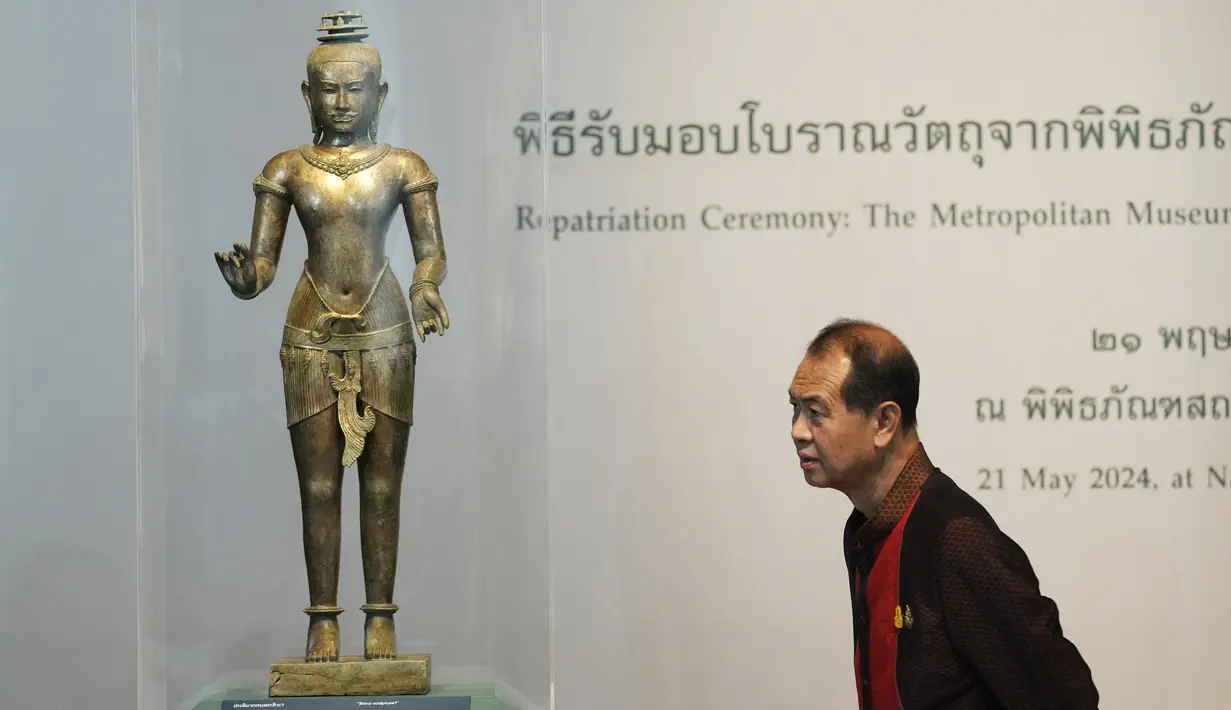 Seorang warga Thailand melihat patung Siwa berdiri dari abad ke-11 saat upacara pemulangan di Museum Nasional di Bangkok, Thailand, Selasa (21/5/2024). (AP Photo/Sakchai Lalit)