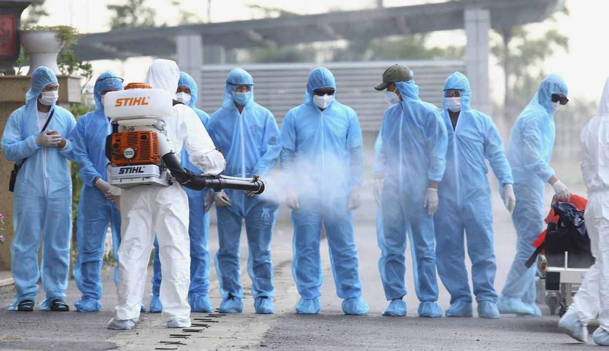 Petugas kesehatan membasmi kuman pada pasien COVID-19 asal Vietnam yang tiba di rumah sakit nasional penyakit tropis di Hanoi, Vietnam, Rabu (29/7/2020). Sebanyak 129 pekerja asal Vietnam dipulangkan dari Equatorial Guinea untuk mendapat perawatan COVID-19.  (Bui Cuong Quyet/VNA via AP)