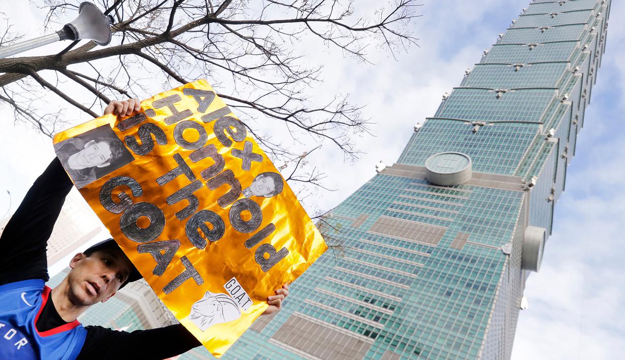 Seorang warga memberikan dukungan untuk atlet panjat tebing 'free solo' asal Amerika, Alex Honnold saat memanjat gedung Taipei 101 tanpa tali pengaman di Taipei, Minggu (25/01/2026). (AP Photo/Chiang Ying-ying)