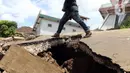 Warga berjalan melintasi jalan yang rusak akibat gempa di Desa Sarampad, Kabupaten Cianjur, Jawa Barat, Selasa (22/11/2022). Gempa dengan magnitudo 5,6 mengakibatkan sejumlah rumah dan jalan di Desa Sarampad rusak parah. (Liputan6.com/Herman Zakharia)