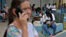 Orang-orang menggunakan ponsel dan laptop untuk terhubung ke internet melalui WiFi di sebuah taman di Havana, Rabu (5/12). Untuk pertama kalinya, masyarakat Kuba berkesempatan dapat mengakses internet dari ponsel mereka pada Kamis ini, (YAMIL LAGE/AFP)