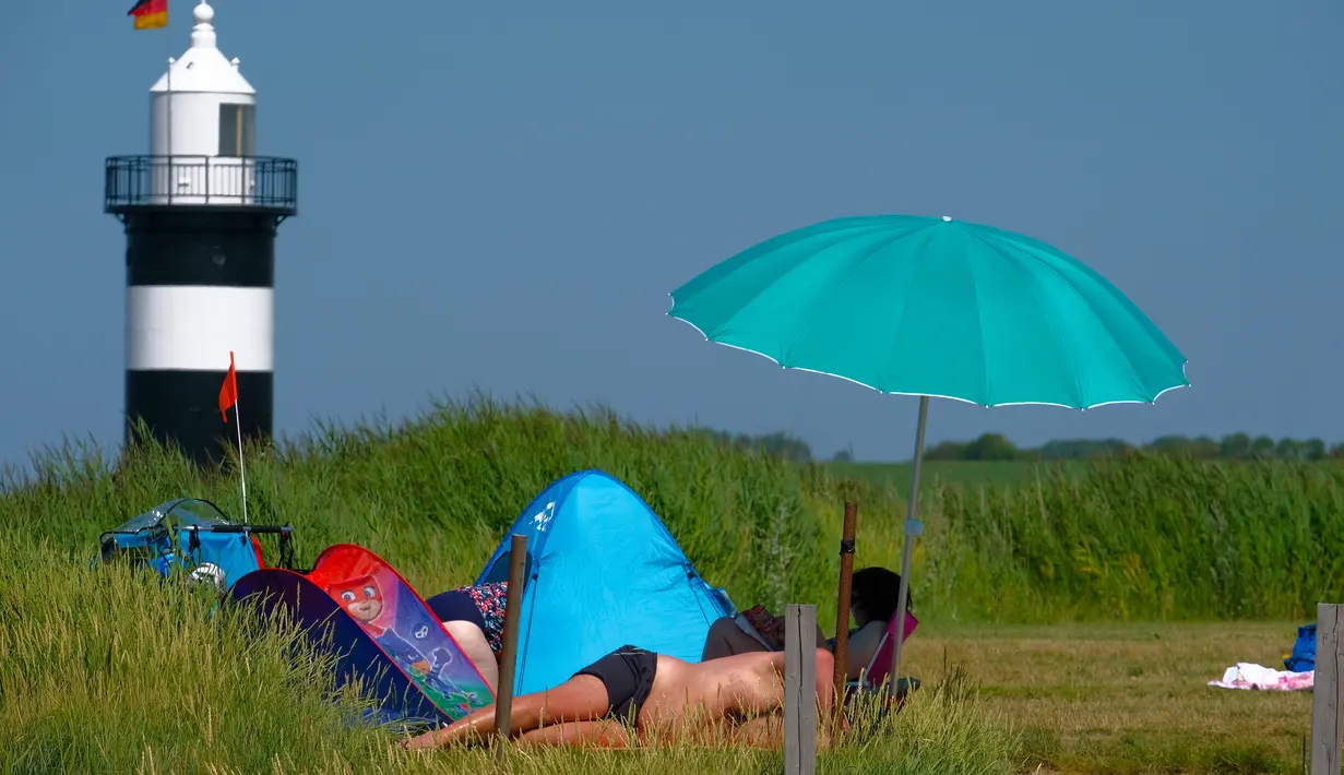 Warga berjemur saat suhu mencapai 34 derajat Celcius di dekat pantai Laut Utara di Wremen, Jerman barat (24/7/2019). Peramal cuaca memprediksi suhu tertinggi di seluruh Eropa barat yang terkena gelombang panas akan mencetak rekor suhu terbaru.  (AFP Photo/Patrik Stollarz)