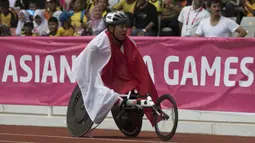 Pebalap kursi roda Indonesia, Jaenal Aripin, melakukan selebrasi usai meraih medali perak pada Asian Para Games cabang atletik nomor balap kursi roda 200 meter T 54 di SUGBK, Jakarta, Jumat (12/10). (Bola.com/Vitalis Yogi Trisna)