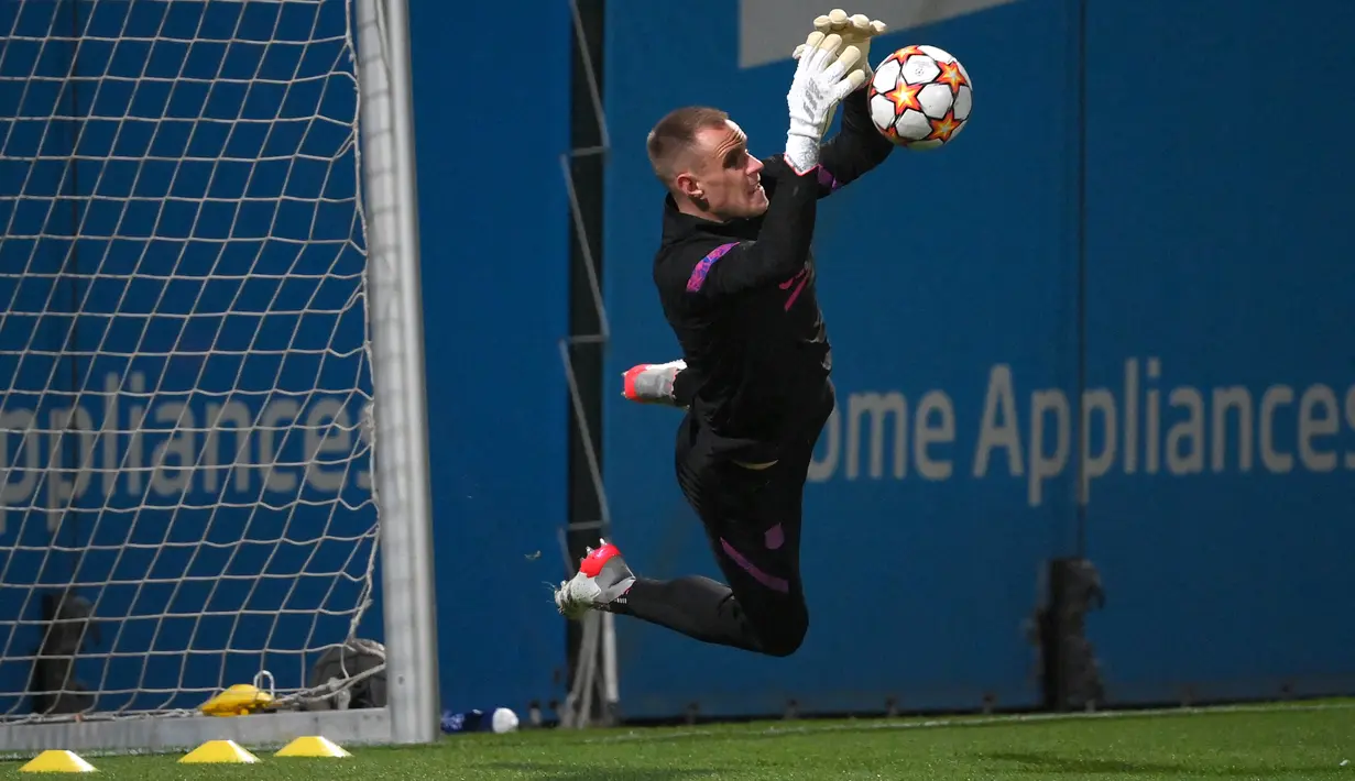 Penjaga gawang Barcelona, Marc-Andre ter Stegen menghentikan bola selama sesi latihan di stadion Camp Nou di Barcelona, Spanyol (22/11/2021). Barcelona akan bertanding melawan Benfica pada Grup E Liga Champions di Camp Nou. (AFP/Gen Lluis)
