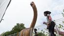 Anak-anak meluncur melewati model dinosaurus seukuran aslinya, Brachiosaurus di sepanjang "Changi Jurassic Mile" jalan santai di Singapura (13/10/2020). (AFP/Roslan Rahman)