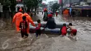 Sejumlah anak bersama petugas membantu warga melewati banjir yang merendam kawasan Benhil RT 03 RW 05, Jakarta Pusat, Selasa (21/1). Hujan deras yang mengguyur sejak Selasa dinihari mengakibatkan kawasan itu mengalami banjir. (Liputan6.com/Johan Tallo)