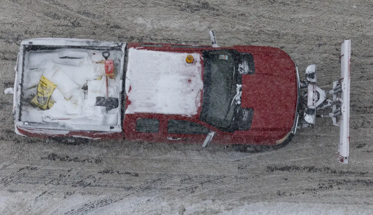 Mobil Bajak salju melaju di sepanjang West Michigan Avenue di pusat kota Kalamazoo, Michigan, Rabu (2/2/2022). Badai musim dingin besar dengan jutaan orang Amerika di jalurnya membawa campuran hujan dan salju ke bagian tengah Amerika Serikat. (Joel Bissell/Kalamazoo Gazette via AP)