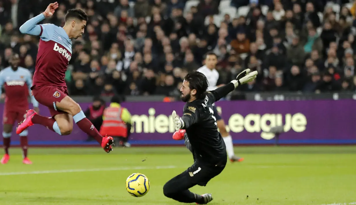 Kiper Liverpool Alisson berusaha menyelamatkan bola tendangan pemain West Ham, Manuel Lanzini pada pertandingan Liga Inggris di Stadion London, Rabu (29/1/2020). Liverpool menang 2-0 atas West Ham dan tetap kokoh di puncak klasemen dengan poin 70. (AP Photo/Frank Augstein)