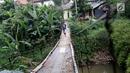 Warga melintasi jembatan penyeberangan buatan warga di kawasan Lenteng Agung, Jakarta, Rabu (24/5). Meskipun kondisinya memprihatinkan, warga setempat tetap menggunakan jembatan tersebut. (Liputan6.com/Immanuel Antonius)