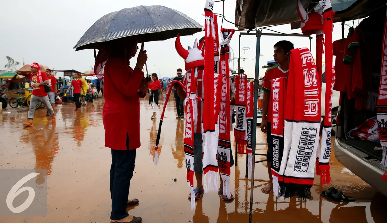 Seorang pendukung Tim Nasional Indonesia melihat atribut bola sebelum pertandingan final leg pertama Piala AFF 2016 dimulai di Stadion Pakansari, Bogor, Rabu (14/12). (Liputan6.com/Johan Tallo)