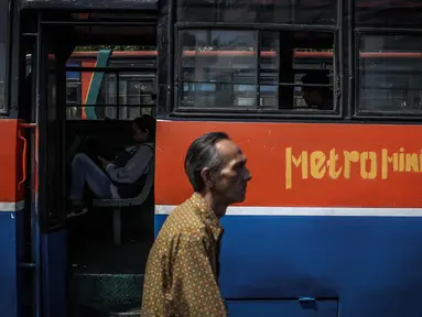 Seorang pria melintas diantara Metromini di Terminal Blok M, Jakarta, Rabu (26/7). Dinas Perhubungan (Dishub) DKI Jakarta akan merevitalisasi 700 unit metromini menjadi Minitrans. (Liputan6.com/Faizal Fanani)