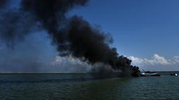 Asap hitam mengepul dari kapal asing ilegal yang ditenggelamkan di perairan Pelabuhan Perikanan Samudera Kutaraja, Banda Aceh, Aceh, Kamis (18/3/2021). Dua kapal asing asal Malaysia tersebut ditenggelamkan setelah diputus bersalah dalam perkara tindak pidana perikanan. (AFP/Chaideer Mahyuddin)