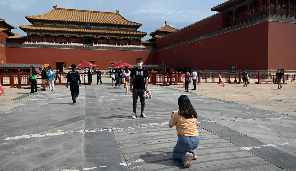 <p>Seorang pria berpose di pintu masuk Kota Terlarang di Beijing, China, Selasa (7/6/2022). Pemerintah melonggarkan beberapa pembatasan Covid-19 dengan sebagian besar museum gedung bioskop, dan pusat kebugaran diizinkan beroperasi hingga 75 persen dari kapasitas. (WANG Zhao / AFP)</p>