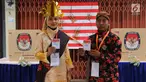 Petugas KPPS memegang surat suara pelaksanaan Pilkada Serentak 2018 di TPS XII Kelurahan Sei Mati, Kecamatan Medan Maimun, Rabu (27/6). Baju adat dari berbagai daerah dan suku tampak dikenakan oleh petugas TPS. (Liputan6.com/Reza Perdana)