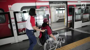 Petugas membantu penyandang disabilitas naiki ke kereta Lintas Rel Terpadu (LRT) di Stasiun LRT Veldrome, Jakarta, Sabtu (27/4). Kegiatan yang diikuti Jakarta Barrier Free Tourism (JBFT) itu untuk mengenalkan LRT lebih dekat, terutama kepada penyandang disabilitas. (Liputan6.com/Faizal Fanani)