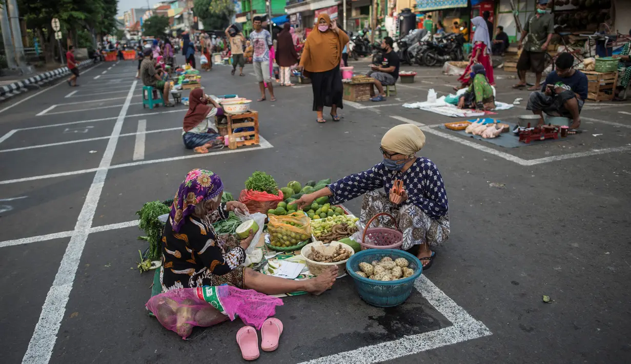 Pedagang menunggu pembeli di dalam garis petak-petak untuk menerapkan jaga jarak (physical distancing) di sepanjang jalan di Surabaya, Selasa (2/6/2020). Garis petak-petak bagi pedagang itu sebagai langkah pencegahan penyebaran COVID-19. (Photo by Juni Kriswanto / AFP)