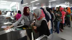 Petugas membantu calon penumpang melakukan tap kartu saat akan menggunakan layanan transportasi Moda Raya Terpadu (MRT) di Stasiun Bundaran HI, Jakarta, Rabu (3/4). Meski sudah tidak digratiskan, warga tetap antusias menjajal MRT. (merdeka.com/Imam Buhori)