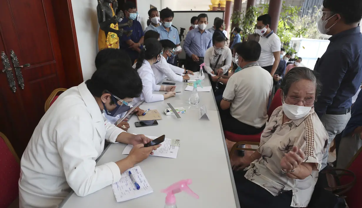 Anggota jurnalis (kanan) berbicara dengan petugas medis sebelum menerima vaksin COVID-19 Sinovac di Phnom Penh, Kamboja, Kamis  (1/4/2021).  Sekitar lima ribu warga Kamboja termasuk jurnalis dan anggota kementerian mulai menerima sebagian dari 1,5 juta dosis vaksin Sinovac. (AP Photo/Heng Sinith)