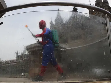 Pekerja sosial India Ashok Kurmi berpakaian seperti Spider Man mendesinfeksi daerah di sekitar stasiun kereta Chhatrapati Shivaji Maharaj selama lockdown yang diberlakukan di Mumbai, Rabu (21/4/2021). Kegiatan tersebut dilakukan untuk mengekang penyebaran COVID-19 di Mumbai. (AP Photo/Rajanish Kakad
