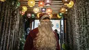 Seorang pramusaji Palestina berpakaian berpakaian Sinterklas menyambut pengunjung di pintu masuk sebuah restoran di pantai di Kota Gaza, Minggu (13/12/2020). Restoran tersebut didandani dengan tema Natal, pelayanannya pun berpakaian seperti Sinterklas. (AP Photo/Khalil Hamra)
