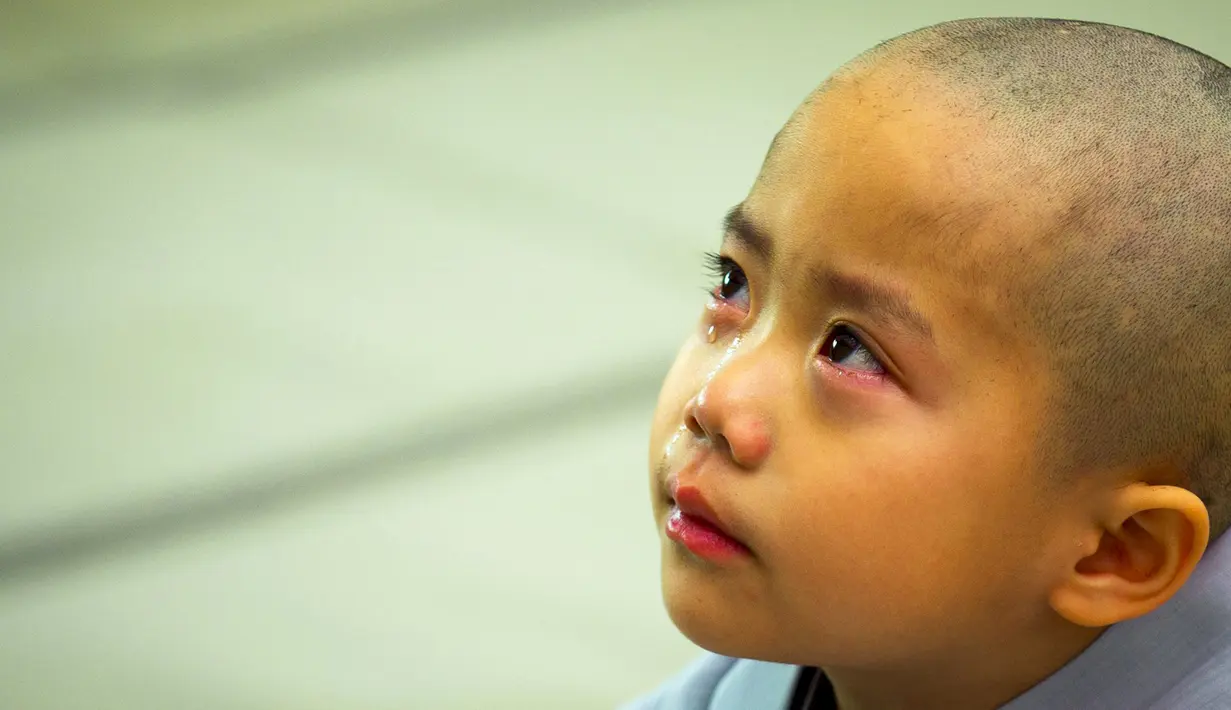 Seorang anak terlihat menangis usai rambutnya dicukur saat upacara pemberkatan Biksu di kuil Jogye, Seoul, Senin (11/5/2015). Upacara ini diadakan bertepatan dengan hari ulang tahun Buddha. (REUTERS/Thomas Peter)