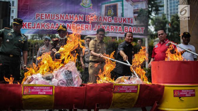 Petugas Kejaksaan bersama pihak kepolisian dan pengadilan membakar barang bukti tindak pidana umum di lapangan Kejaksaan Negeri Jakarta Barat, Selasa (11/12). (Liputan6.com/Faizal Fanani)