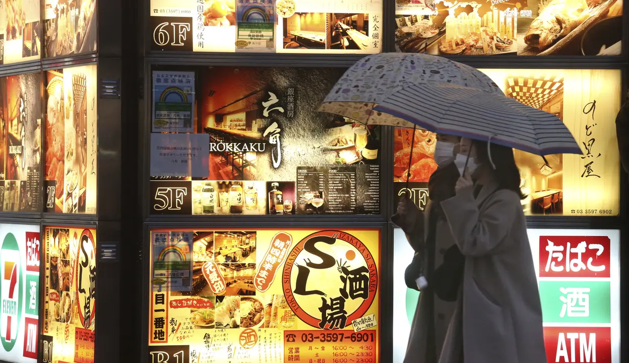 Dua wanita mengenakan masker untuk membantu melindungi diri dari penyebaran virus corona berjalan di sepanjang jalan yang dipenuhi bar dan restoran di Tokyo, Selasa (22/3/2022). Langkah-langkah pra-darurat untuk mencegah wabah Covid-19 telah dicabut. (AP Photo/Koji Sasahara)