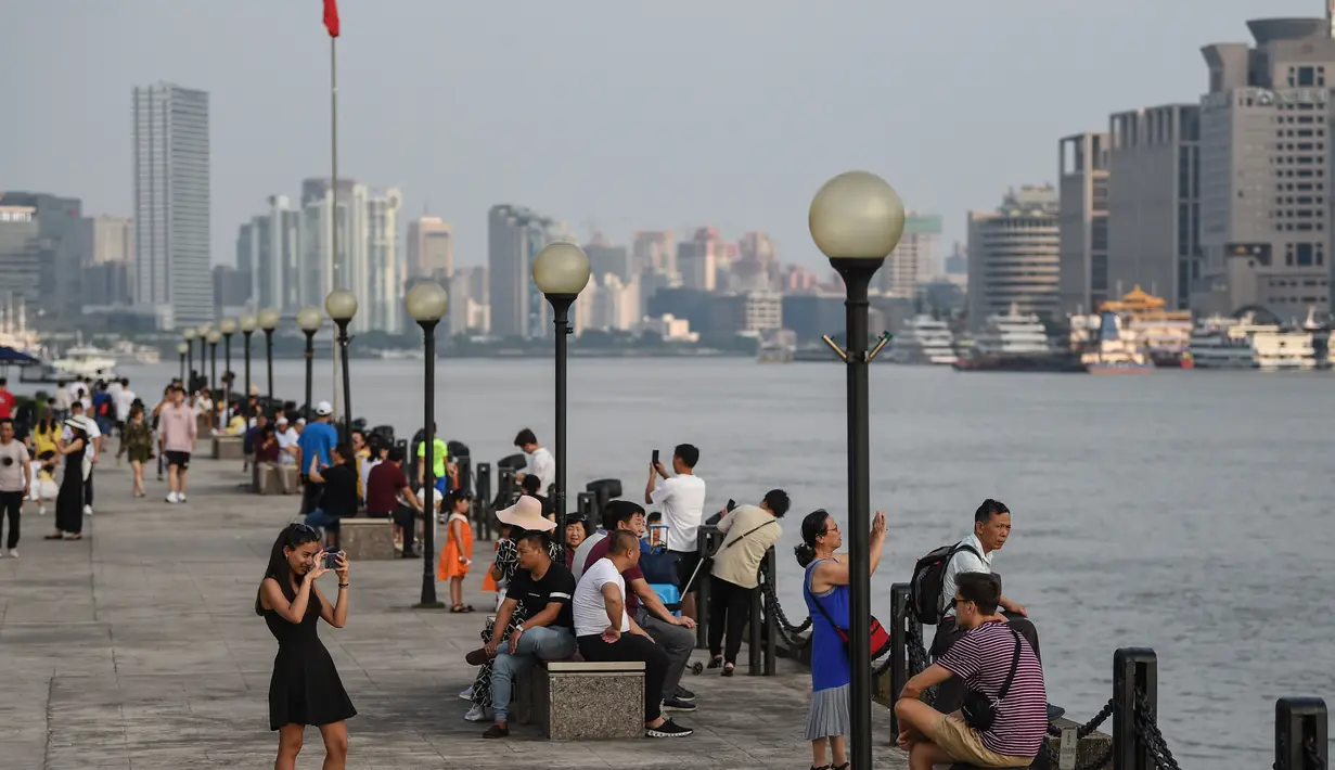 Sejumlah warga menikmati Sungai Huangpu di distrik keuangan Lujiazui di kota Shanghai (15/7/2019). Lebar rata-rata sungai ini adalah 400 meter dan kedalaman rata-ratanya 9 meter. (AFP Photo/Hector Retamal)