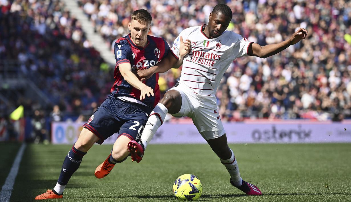 Pemain AC Milan, Fode Ballo Toure (kanan) berebut bola dengan pemain Bologna, Michel Aebischer pada laga lanjutan Liga Italia 2022/2023 di Renato-Dall'Ara Stadium, Bologna, Minggu (16/04/2023) WIB. Laga berakhir dengan skor imbang 1-1. (AP Photo/LaPresse/Massimo Paolone)