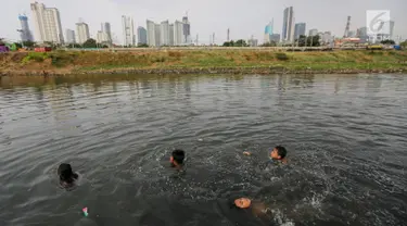 Anak-anak berenang di Kanal Banjir Barat (KBB) yang hitam di Petamburan, Jakarta, Senin (12/8/2019). Surutnya debit air KBB akibat musim kemarau dimanfaatkan anak-anak untuk bermain sambil mencari ikan. (Liputan6.com/Fery Pradolo)