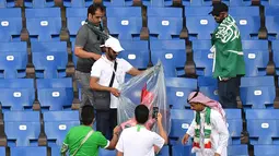 Suporter Arab Saudi memunguti sampah di tribun seusai laga melawan Uruguay pada pertandingan kedua Grup A Piala Dunia 2018 di Rostov Arena, Rostov-on-Don, Rabu (20/6). Kalah 0-1, Arab Saudi menjadi tim kedua yang tersingkir setelah Maroko (AFP/JOE KLAMAR)