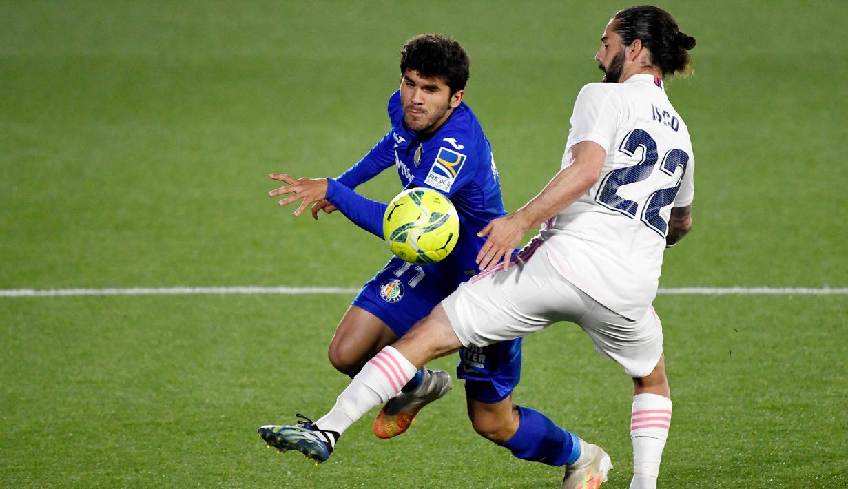Gelandang Real Madrid, Isco, berusaha menghadang pemain Getafe, Carles Alena, pada laga Liga Spanyol di Stadion Alfonso Perez, Senin (19/4/2021). Kedua tim bermain imbang 0-0. (Photo by PIERRE-PHILIPPE MARCOU / AFP)
