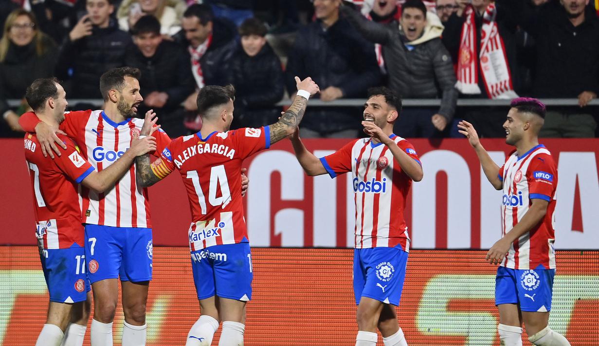 Keganasan Girona terus berlanjut di Liga Spanyol 2023/2024. Atletico Madrid menjadi korban teranyar tim asuhan pelatih Michel lewat kemenangan dramatis 4-3 dalam laga pekan ke-19 yang digelar di Montilivi Stadium, Girona, Kamis (4/1/2024) dini hari WIB. Empat gol Girona dicetak oleh 4 pemain berbeda, yaitu Valery Fernandez (2'), Savio (26'), Daley Blind (39') dan Ivan Martin (90+1'). Sementara ketiga gol Atletico Madrid dihasilkan lewat hattrick Alvaro Morata (14', 44' dan 54'). Dengan hasil ini Girona yang hanya kalah selisih gol berhasil menyamai poin Real Madrid sebagai pemuncak klasemen dengan raihan 48 poin. (AFP/Pau Barrena)