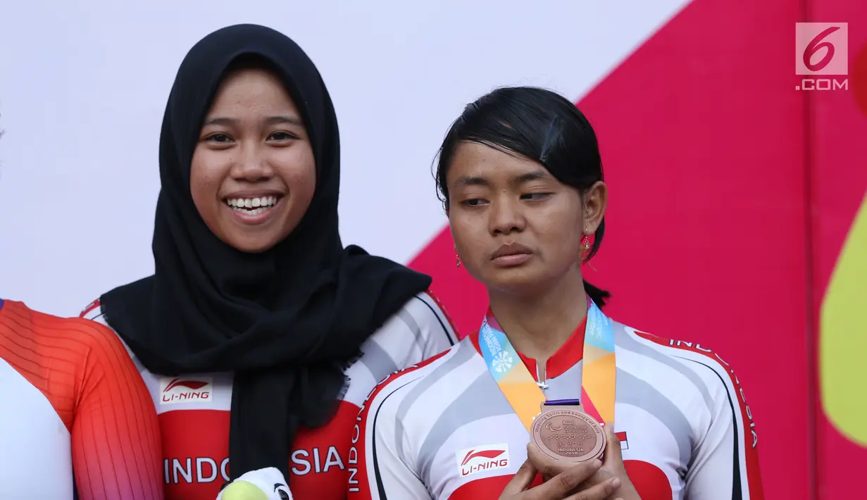 Atlet ParaCycling, Ni Mal Maghfiroh (kiri) dan Sri Sugiyanti saat prosesi pengalungan medali nomor Womens B Individual Time Trial Road Race Asian Para Games 2018 di Sirkuit Sentul, Bogor, Senin (8/10). (Liputan6.com/Helmi Fithriansyah)