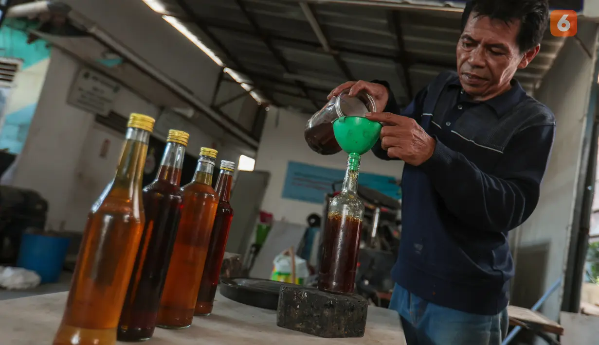 Pengurus RW 01 menuangkan bahan bakar alternatif sejenis petasol kedalam botol hasil dari proses pengolahan sampah plastik di Jakarta, Senin (19/10/2026). (KLY/Budy Santoso)