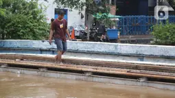 Seorang pria melintas di antara genangan banjir di Jalan dr Sutomo, Pasar Baru, Jakarta, Selasa (25/2/2020). Hujan yang mengguyur Jakarta sejak Senin (24/2) malam membuat sejumlah kali meluap dan menyebabkan banjir. (Liputan6.com/Helmi Fithriansyah)