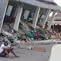 Seorang pria memeriksa ponselnya di dekat bangunan yang runtuh akibat gempa bumi di Reok, Provinsi Nusa Tenggara Timur, Indonesia, Minggu, 16 Agustus 2026. (Foto AP/Aquila Handayani Abbas)