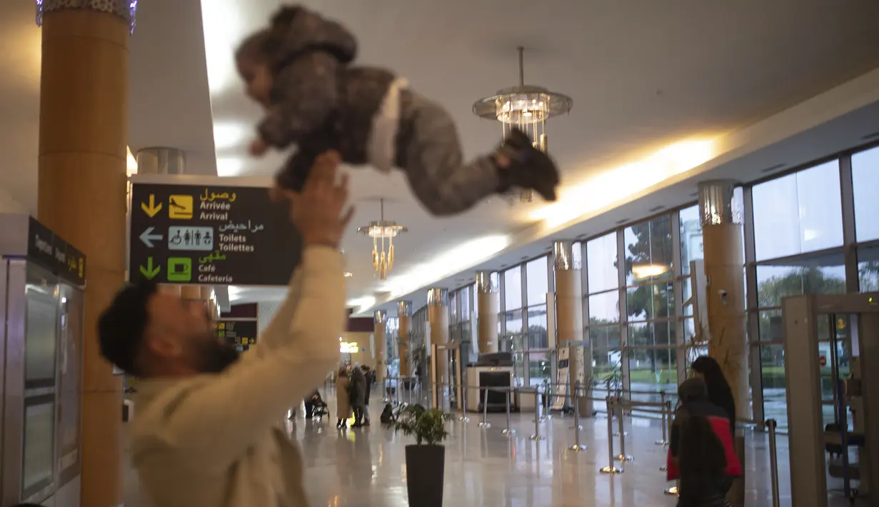 Seorang pria bermain dengan anak ketika menunggu untuk berangkat di terminal bandara Rabat, Maroko, Senin (29/11/2021). Maroko menangguhkan semua penerbangan internasional mulai Senin tengah malam selama dua minggu karena kekhawatiran pada varian baru Covid-19 Omicron. (AP Photo/Mosa'ab Elshamy)