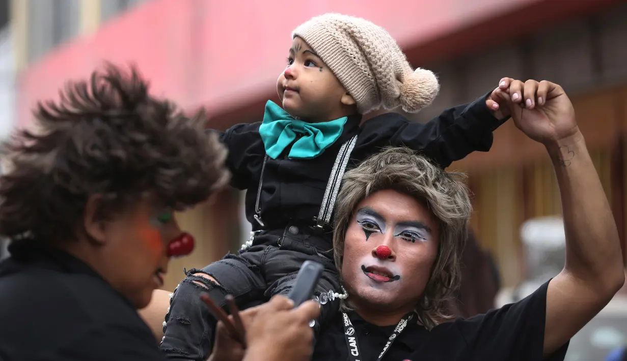 Seorang badut menggendong anaknya di atas bahu saat berpartisipasi dalam acara Hari Badut Nasional di ibu kota Peru, Lima, Kamis(25/5). Tanggal 25 Mei merupakan peringatan Hari Badut Nasional bagi warga Peru. (AP Photo/Martin Mejia)