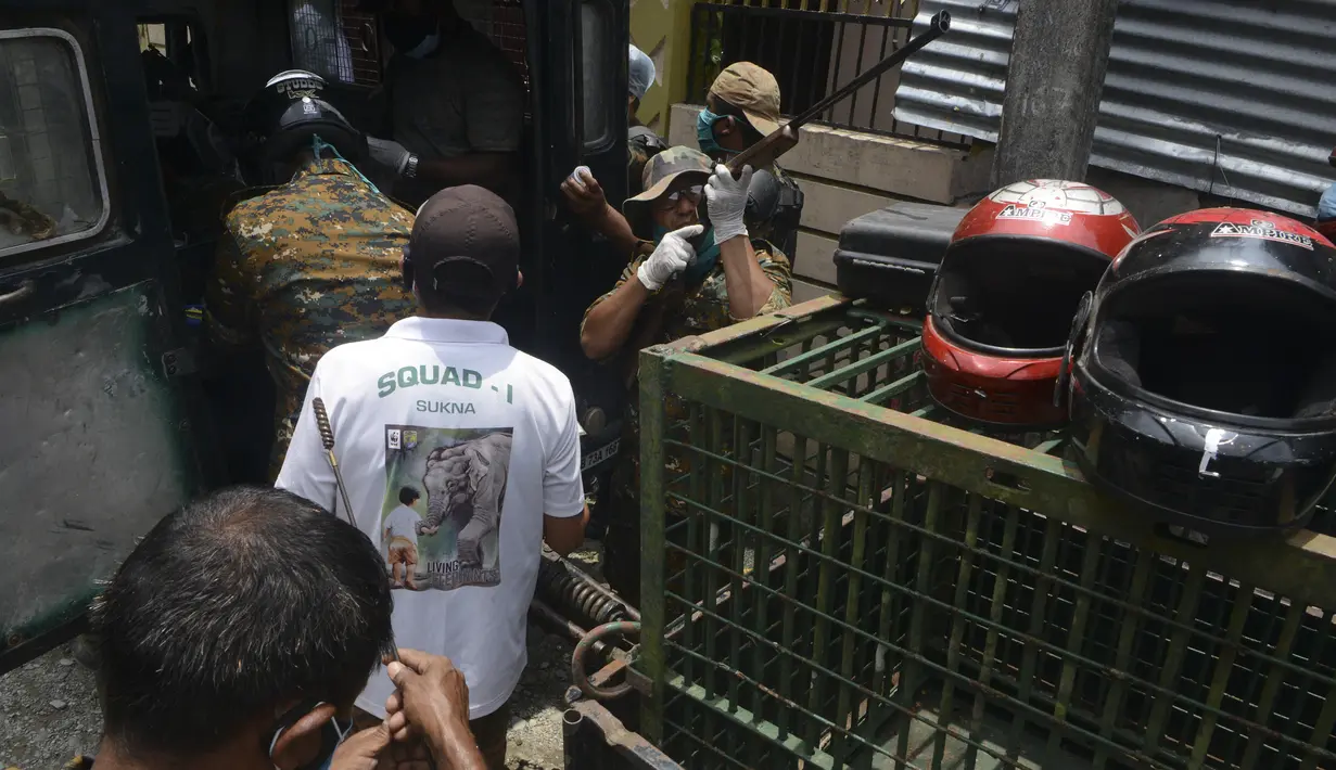 Penjaga hutan menyiapkan senapan berisi peluru obat bius untuk menangkap macan tutul liar di daerah permukiman di desa Samarnagar di pinggiran Siliguri, India, pada Senin (17/5/2021). Macan tutul liar itu diduga tersesat hingga masuk ke pemukiman penduduk. (Photo by DIPTENDU DUTTA / AFP)