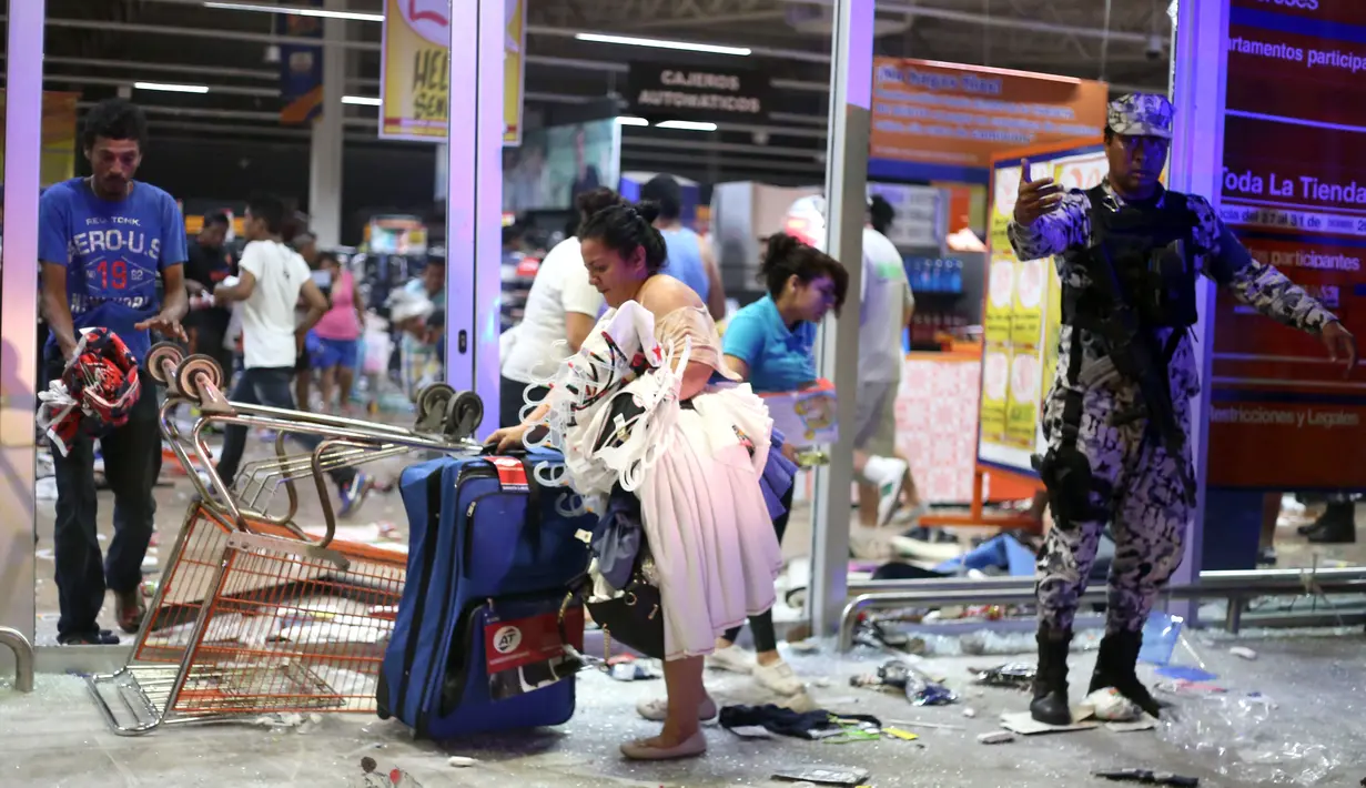 Orang-orang membawa sejumlah barang usai menjarah sebuah toko di negara bagian Veracruz, Meksiko, Rabu (4/1). Penjarahan terjadi di sejumlah toko di Meksiko, seiring berlangsungnya unjuk rasa memprotes kenaikan harga bahan bakar minyak. (Ilse HUESCA/AFP)