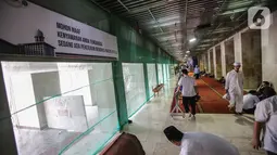 Jemaah merapikan karpet usai melaksanakan salat Jumat di samping renovasi Mesjid Istiqlal, Jakarta, Jumat (1/11/2019). Renovasi ditargetkan rampung pada Maret 2020 sehingga dapat dimanfaatkan pada Bulan Ramadan tahun depan. (Liputan6.com/Faizal Fanani)