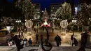 Orang-orang mengambil gambar alun-alun Syntagma yang diterangi dekorasi Natal di pusat kota Athena, Yunani pada 21 Desember 2020. Yunani akan merayakan musim Natal di bawah langkah-langkah penguncian wilayah atau lockdown COVID-19 hingga 7 Januari 2021 mendatang. (LOUISA GOULIAMAKI/AFP)