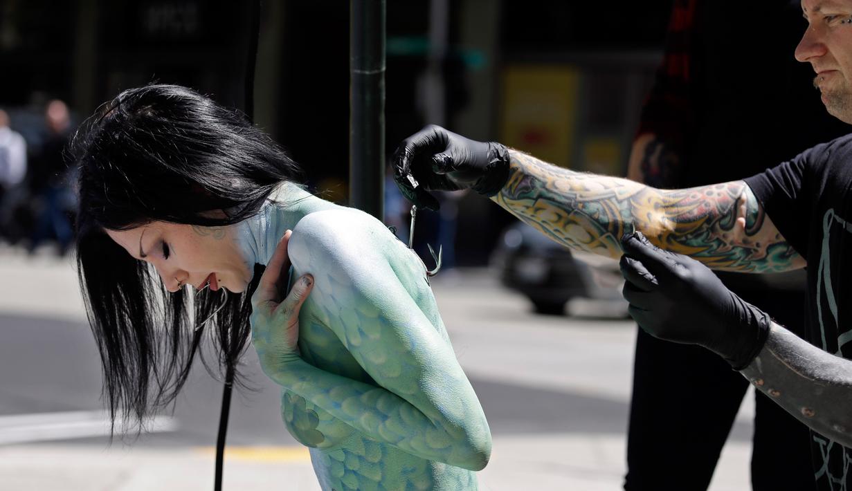 Tim mengait punggung Victoria Lemeow jelang aksi menolak penangkapan ikan di Seattle, AS, Senin (5/6). Aksi yang disponsori PETA  ini sebagai protes terhadap SeaWeb Seafood Summit yang diadakan di kawasan tersebut. (AP Photo / Elaine Thompson)