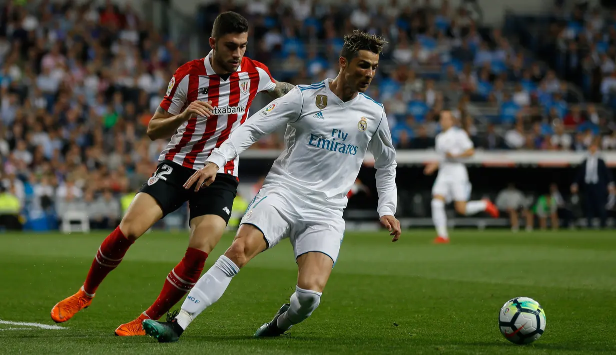 Pemain Real Madrid, Cristiano Ronaldo berebut bola dengan pemain Athletic Bilbao, Unai Nunez pada pekan ke-33 La Liga di Santiago Bernabeu,Rabu (18/4). Real Madrid harus puas bermain imbang 1-1 lawan Athletic Bilbao. (AP/Francisco Seco)