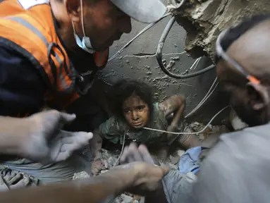 Warga Palestina mencoba menarik seorang anak keluar dari reruntuhan bangunan yang hancur akibat serangan udara Israel di kamp pengungsi Jabaliya, Jalur Gaza utara, Rabu, 1 November 2023. (AP Photo/Abed Khaled)