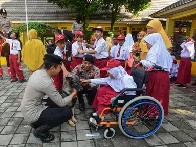 Salah satu siswa didampingi personel Direktorat Polisi Satwa (Ditpolsatwa) berinteraksi dengan anjing pelacak K-9 di Sekolah Luar Biasa Negeri (SLBN) kota Depok, Jawa Barat, Senin (2/6/2025). (merdeka.com/Arie Basuki)