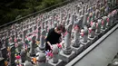 Seorang wanita menyalakan lilin di depan patung Jizo yang didedikasikan untuk jiwa anak-anak yang telah meninggal dunia di Kuil Buddha Jizoji, Oganomachi, Prefektur Saitama, Jepang, Senin (13/8). (Behrouz Mehri/AFP)